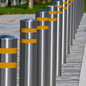 Row of metal bollards with bands of reflective material, positioned at the side of the road